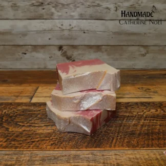 Peppermint Candy handmade Hand & Body Soap with refreshing red and white candy cane-inspired swirls, placed on a rustic wooden surface, created by Catherine Noel.