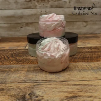 Apple Harvest whipped body butter with creamy swirls in rich golden tones, displayed in a clear jar with a black lid on a rustic wooden surface.