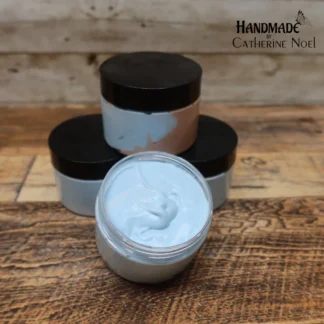 Bloke whipped body butter with creamy swirls in earthy blue and brown tones, displayed in a clear jar with a black lid on a rustic wooden surface.