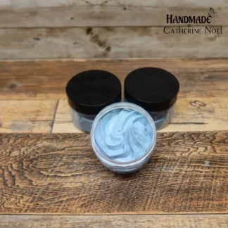 Blueberry Delight whipped body butter with vibrant blue swirls, displayed in a clear jar with a black lid on a rustic wooden surface.