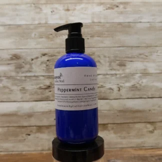Peppermint Candy Hand & Body Lotion in a vibrant blue bottle, displayed against a rustic wooden background.