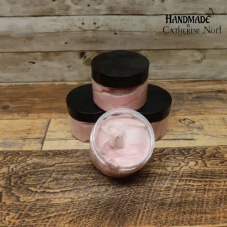 Peppermint Candy whipped body butter with white and red candy cane-inspired swirls in a clear jar with a black lid, displayed on a rustic wooden surface.